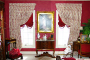 Master bedroom drapes in red and cream toile with balloon shades trimmed with tassels 
