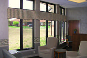 The curved wall of the office waiting room windows have a continuous quilted valance to pull all three windows together.

