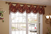 Swaged valance with tassel fringe on antique gold wood rod compliment paint color in the dining room.
