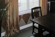 Terra-cotta and gold faux silk drapery panels mounted on wrought iron rod 
