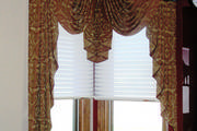 Corner window treatment with swags and cascades in a jacquard fabric with micro piping in red.
