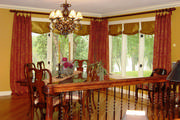 Floor length drapes in a beautiful brocade with golden silk roman shades frame the dining room corner windows.

