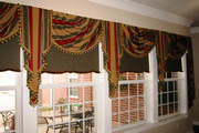 Striped swags and cascades with tassel trim over coordinating roller shades. 
