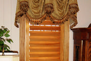 Golden swagged valance with tassel trim softens the look of the plantation shutters.
