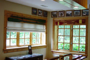 Antique wooden oars attached to cedar cornices with linen roman shades add to the rustic feel of the room.
