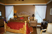 White linen drapery mounted on wrought iron rods with silhouette shades in Master bedroom
