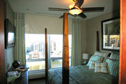 High rise condo bedroom pleated drapes with motorized shades. Bedding, drapes and pillows in cream, blue and green
