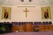 Fabric banners in a stained glass motif mounted on gold wood poles with bullion fringe along the bottom.
