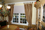 Tone on tone camel stripe drapes mounted on tab posts with gold silk tassel tiebacks  
