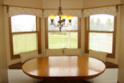 Arching valance in a kitchen bay window with coordinating pillows and faux alligator skin seat cushions
