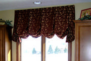 A box pleated balloon shade in red and gold jacquard over the kitchen sink.
