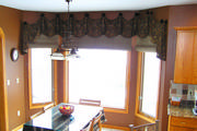 For this arched window a roman shades was used along with a draped valance in brown and gold paisley.
