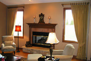 gold embroidered drapes with tiebacks frame out the fireplace in this family room.
