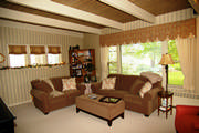 A scalloped valance in paisley and plaid with sheers as well as roman shades soften the lines in the wallpaper and beams.
